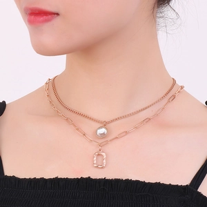 Close-up of rose gold layered necklace featuring square and round crystal pendants