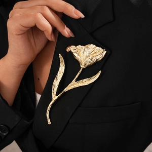 Close-up of golden textured tulip flower brooch on a black suit lapel with metal finish