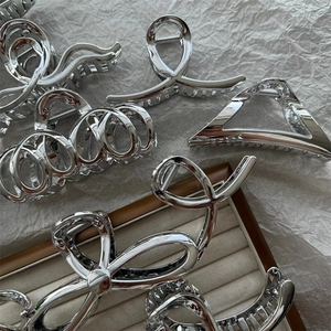 Detail view of silver metal shark hair claws in butterfly and geometric designs