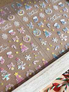 Detail showing laser Christmas nail stickers with snowflakes and trees on brown backing