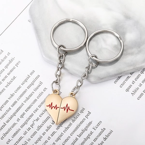 Close-up of magnetic heart pendants with red heartbeat lines on creative gold keychains