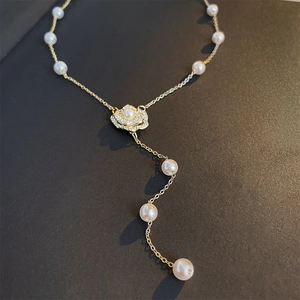 Gros plan détaillé d'un pendentif fleur doré avec perles et cristaux sur fond noir mat