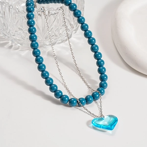 Close-up of double-layer beaded necklace with blue heart glass pendant and resin beads