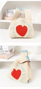 Detailed texture of cream knitted tote bag featuring a red heart and blue lettering