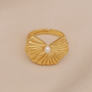 Detailed macro view of a golden shell-shaped ring featuring a white pearl in the center