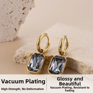 Detail of square-shaped gold drop earrings with smoky faceted gems on a stone tray