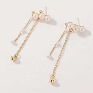 Detail of long gold tassel earrings featuring white pearls and polished metallic beads