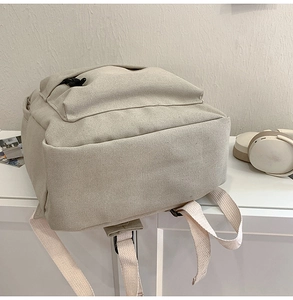 Detail view of the durable cream canvas backpack side pocket and reinforced shoulder straps