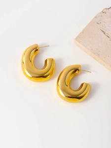 Detailed view of polished gold C-shape chunky earrings on a minimalist background