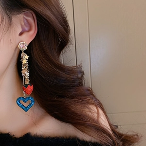 Detailed view of long tassel earrings with strawberry, star, and heart charms on model