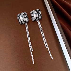 Detail of vintage square stud earrings featuring black enamel, diamonds, and long tassels