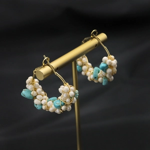 Handmade hoop earrings with turquoise stones and white pearls on a gold stand