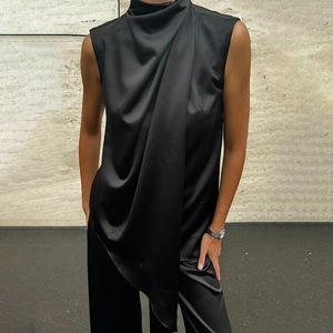 Detailed view of the black sleeveless top featuring elegant draped pleats and silky fabric