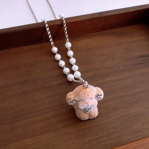 Macro detail of plush puppy pendant with white pearls on a minimalist metal chain