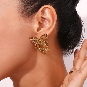 Macro view of gold plated double butterfly earrings showing intricate wing textures