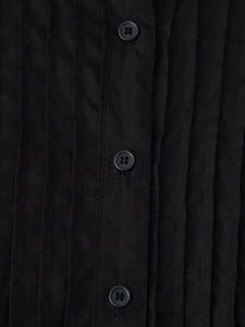 Detail view of the pleated chest design and single-breasted buttons on a black dress