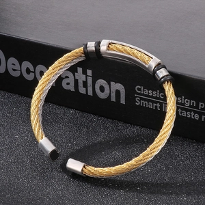 Close-up of gold and silver twisted cable bracelet with rubber accents on a black box