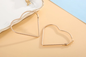 Detailed close-up of large golden heart earrings on a stylish two-tone background