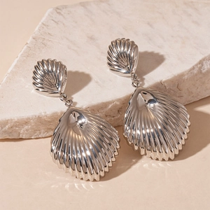 Detail of silver shell earrings with vertical texture on natural stone background