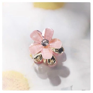Macro shot of pink crystal camellia hair claw with gold metal base and rhinestones