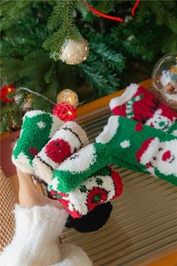 Détail de chaussettes de Noël en polaire corail avec motifs de Père Noël et de rennes