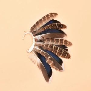 Macro shot of boho peacock feather ear cuff with natural textures and golden metal hook