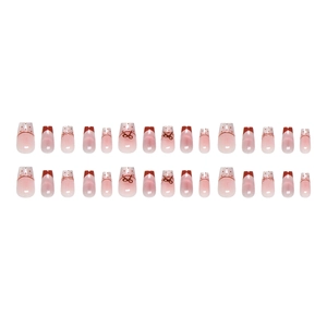 French tip press-on nails with red bow and polka dot designs in pink gradient style