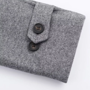 Macro detail of grey textured wool coat fabric with matte black double-hole button