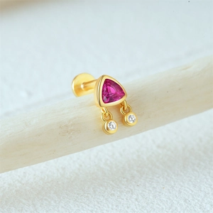 Detailed macro of gold S925 silver ear stud with pink opal and hanging gems on wood