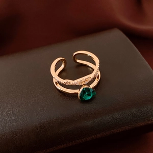 Detail eines 18K vergoldeten Doppelrings mit smaragdgrünem Stein auf Lederunterlage