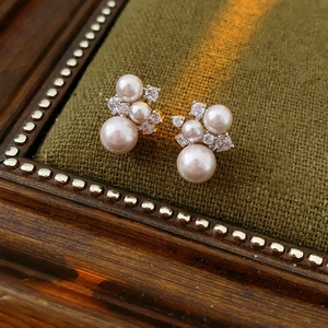 Detail view of pearl and zircon flower earrings on a vintage green velvet jewelry box