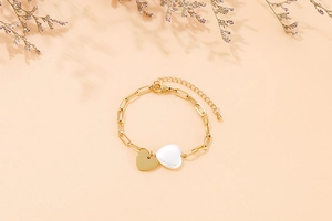 Détail du bracelet en chaîne trombone dorée avec pendentifs en forme de cœur or et blanc