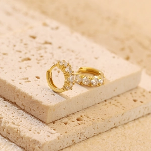 Detailed close-up of gold-plated silver huggie earrings with cubic zirconia stones