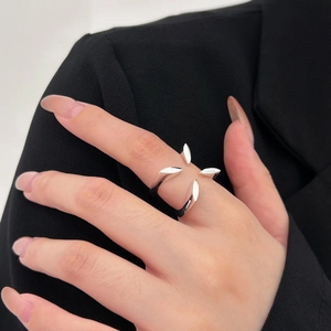 Close-up of minimalist silver ring with four-petal geometric prisms on black fabric