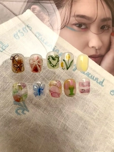 Detail von 10-teiligen Kunstnägeln mit Blumen- und Herzmustern auf Stickereistoff