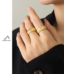 Detail of gold croissant rings in stainless steel worn over a black blazer sleeve