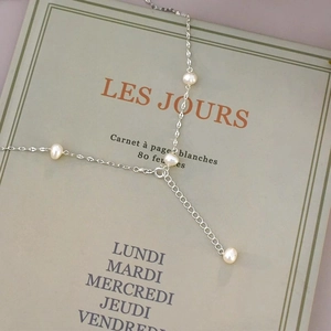 Detail of freshwater pearl necklace with silver chain and adjustable clasp on a notebook