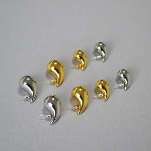 Macro shot of minimalist hollow gold and silver teardrop earrings with high polish finish