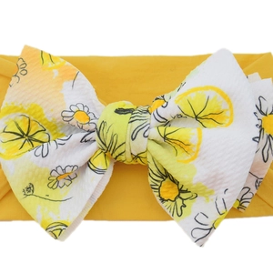 Close-up of yellow baby headband featuring a large lemon and daisy print bow detail