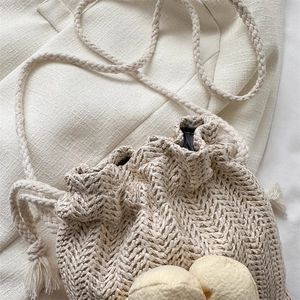 Mini borsa a secchiello in paglia beige chiaro con ciondoli a ciambella e tracolla