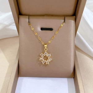 Detail of a sparkling gold necklace with a sunburst zircon pendant in a brown gift box
