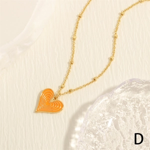 Macro detail of orange heart pendant with ripple texture on gold beaded chain