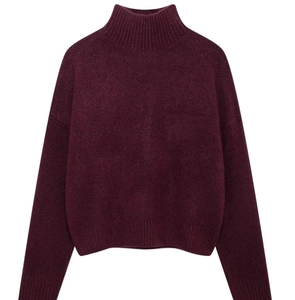 Detail of high turtleneck and ribbed knit texture on a burgundy long sleeve sweater