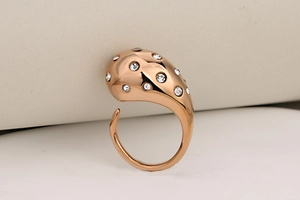 Macro detail of rose gold teardrop ring with scattered crystals and organic shape