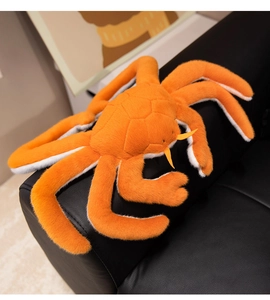 Detail of soft orange plush king crab toy with realistic leg texture on a leather sofa