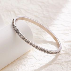 Macro detail of silver titanium steel hinge bracelet with single row of clear zircons