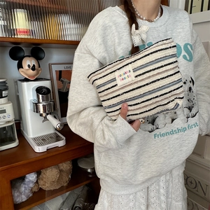 Close-up of a striped canvas pouch featuring a woven label and cozy textured knit fabric