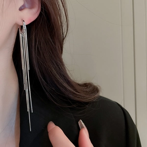 Elegant long silver tassel earrings worn by a model with a sophisticated metallic finish