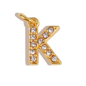 Macro detail of gold letter K charm with micro-pave white crystals and a top bail