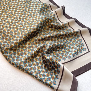 Close-up of geometric silk-like square scarf folded on a white textured surface